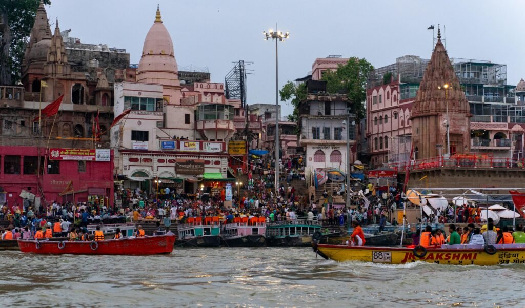 Bustling riverfront scene in Varanasi with boats and traditional architecture.