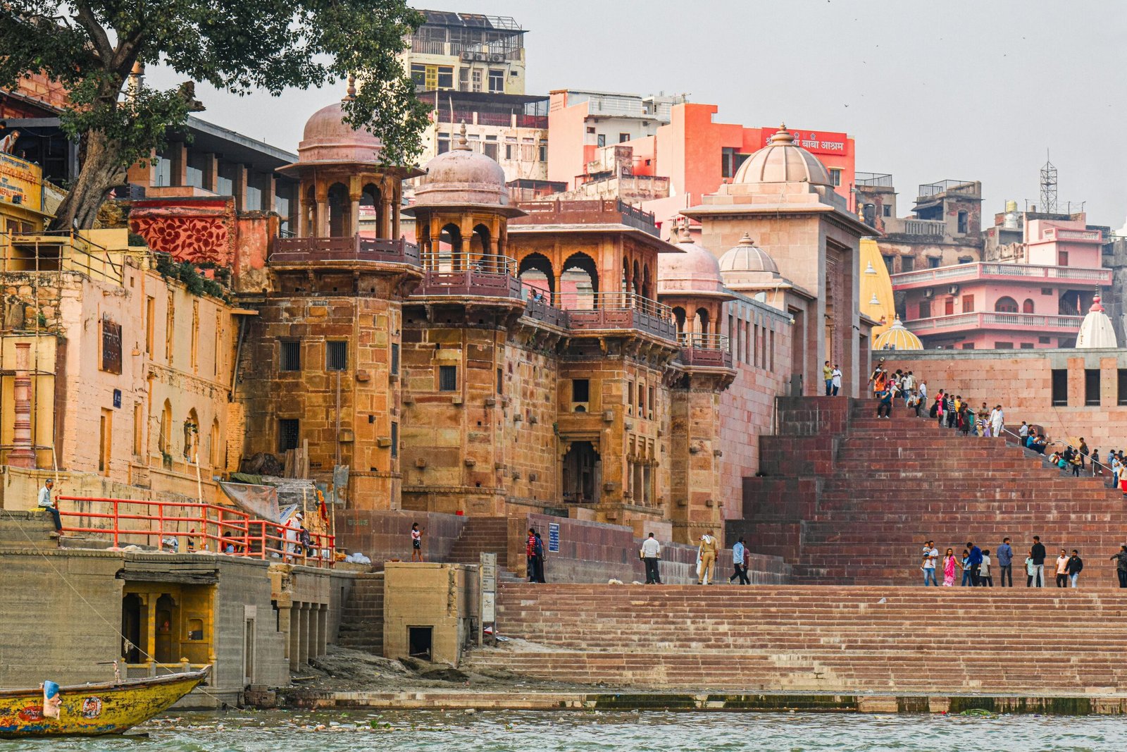 Bustling scene along the Ganges River in Varanasi, showcasing historic architecture and lively locals.